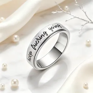 Detail view of engraved 'keep fucking going' text on a stainless steel spinner ring