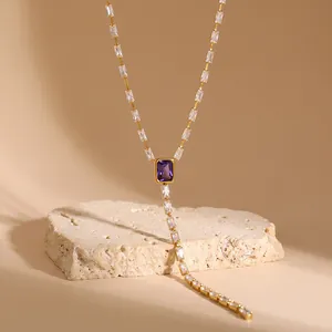 Close-up detail of gold Y-shaped necklace featuring a rectangular purple stone and baguette zircons