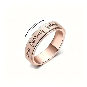 Macro view of rose gold stainless steel spinner ring with 'keep fucking going' engraving