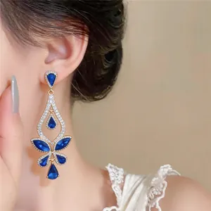 Detailansicht eleganter goldfarbener Hängeohrringe mit blauen Wassertropfensteinen