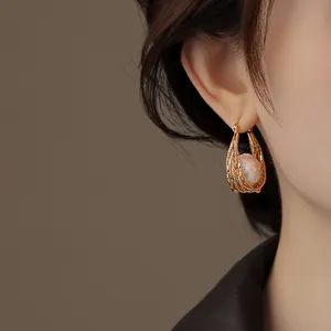 Gros plan d'une boucle d'oreille goutte en or 18 carats avec perle sur modèle