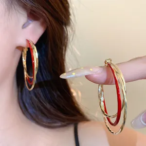 Gros plan détaillé de boucles d'oreilles créoles torsadées rouges et dorées élégantes