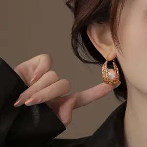 Détail d'une boucle d'oreille plaquée or 18k avec perle et design vintage de style panier