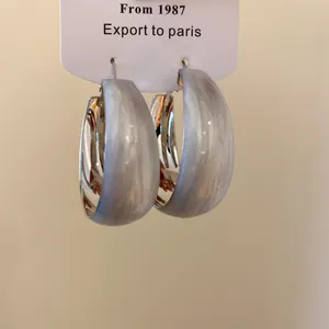 Vue détaillée des boucles d'oreilles créoles avec texture marbrée grise et argent.