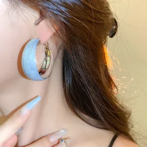Vue détaillée d'une boucle d'oreille créole torsadée bleu clair et argent sur modèle