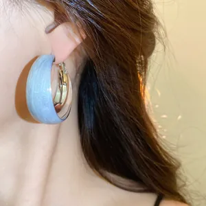 Détail en gros plan d'une boucle d'oreille créole torsadée en argent avec émail bleu clair