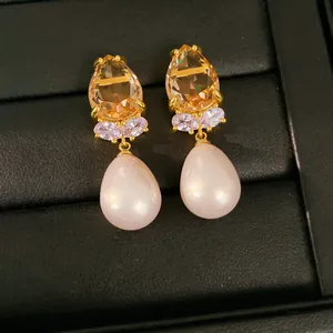 Gros plan de boucles d'oreilles perles dorées avec zircons couleur champagne