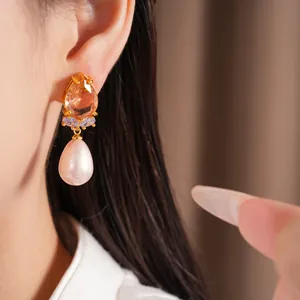 Gros plan détaillé d'une boucle d'oreille goutte d'eau en perle et zircone dorée