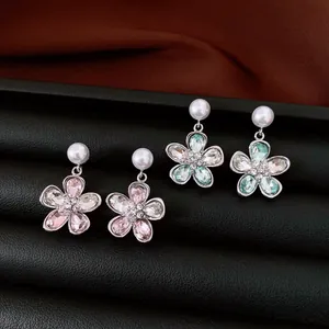 Nahaufnahme eleganter Blumenohrringe mit Perlen und bunten Kristallen auf Schwarz.