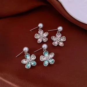 Elegante Kristall- und Perlenblumen-Ohrstecker auf einem braunem Stoffhintergrund.