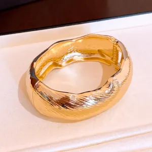 Vue détaillée du bracelet ovale doré ondulé montrant sa texture côtelée unique