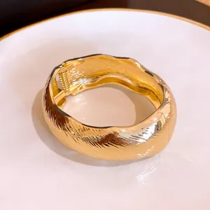Détail d'un bracelet jonc ovale doré texturé vague au style vintage de luxe