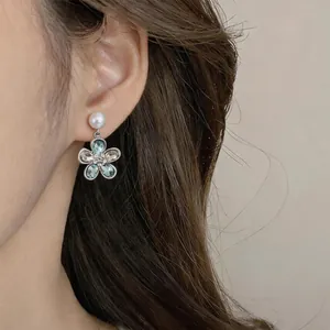 Elegante Ohrringe mit Kristallblumenanhänger und weißem Perlenakzent, am Ohr getragen
