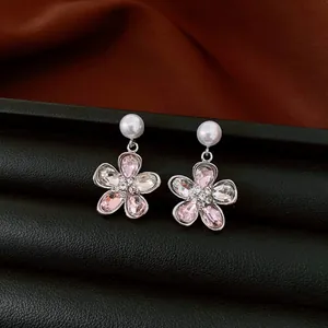 Detailaufnahme eleganter Silbernadellohrringe mit rosa Kristallblumen und Perlen.