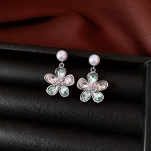Detailansicht eleganter silberner Blumen-Ohrhänger mit Perlen und blauen Kristallen