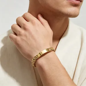Close-up of a gold-plated Byzantine chain bracelet with a smooth ID plate on a wrist.