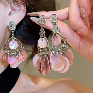 Close-up detail of vintage pink shell fringe earrings featuring bronze metal floral accents