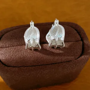 Detalle de elegantes pendientes de aro plateados plisados en caja de joyas