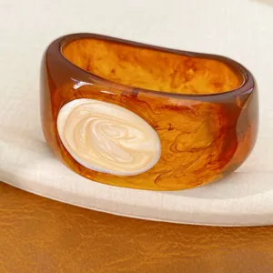 Detailansicht eines klobigen Bernstein-Resin-Armreifs mit cremefarbenem Wirbel-Inlay.