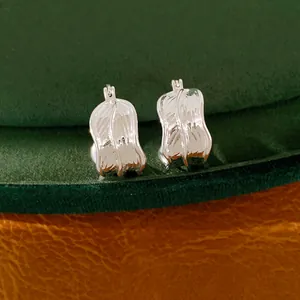 Primer plano de pendientes de aro plateados con elegante textura plisada y brillo