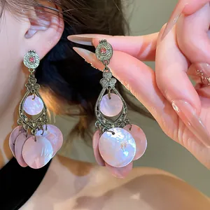 Detail view of vintage bronze earrings with pink shell tassels and sparkling stones