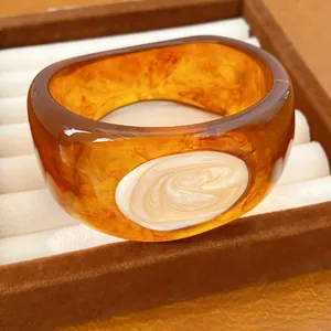 Detailansicht eines breiten Bernstein-Resin-Armreifens mit Marmor-Inlay-Struktur