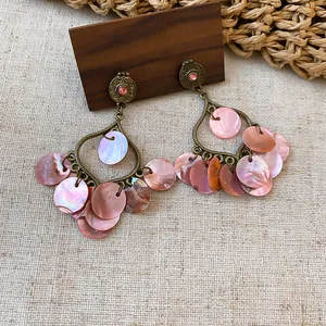 Close-up detail of vintage bronze chandelier earrings featuring iridescent pink shell tassels