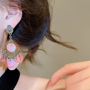 Macro detail of vintage-style pink shell tassel earrings with elegant silver needles