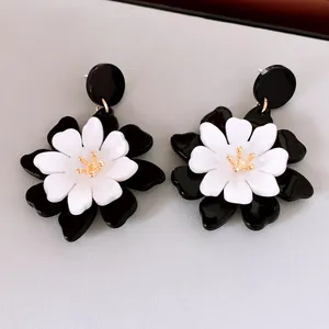 Vue détaillée de boucles d'oreilles fleurs en acrylique noir et blanc avec pistil doré.