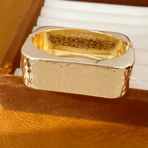 Macro detallada que muestra la textura martillada en la superficie del brazalete dorado