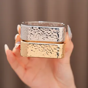 Detalle de brazaletes rectangulares de oro y plata con textura de martillado.