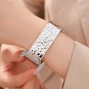 Primer plano de un brazalete plateado con textura martillada en la muñeca de una mujer