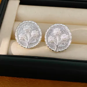 Close-up van zilveren ronde bloemen oorknopjes met parels in een luxe sieradendoos