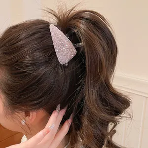 Detailopname van een glinsterende roze kristallen haarklem in een golvend kapsel