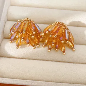 Macro detail showing faceted amber glass beads on golden tassel stud earrings