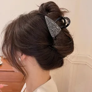 Detailopname van een zwarte haarklem met kristallen op een donkere knot.