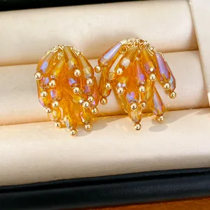 Macro detail view of amber glass fringe earrings in a cream velvet jewelry display box.