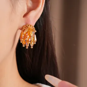 Close-up of elegant amber glass tassel stud earrings in gold-toned finish for women