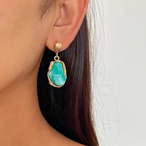 Close-up view of elegant retro irregular teal resin drop earrings with gold