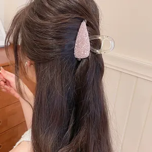 Detailopname van een roze kristallen haarklem gedragen in lang bruin haar voor vrouwen.