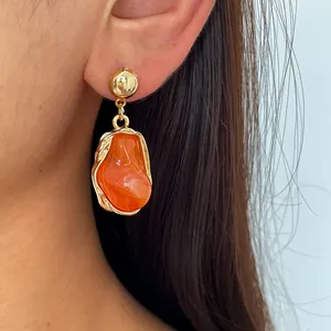 Close-up view of retro orange marbled resin earrings with irregular gold metal frame