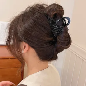 Detail van een zwarte kristallen haarklem die een stijlvolle bruine knot stevig vasthoudt