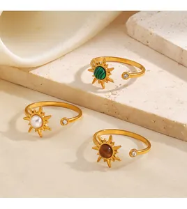Primer plano de anillos dorados con diseño de sol y gemas de colores sobre piedra