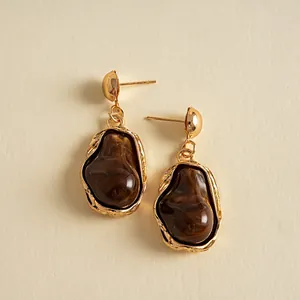 Detailed view of vintage gold earrings with irregular dark brown marbled resin charms