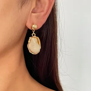 Close-up of vintage irregular geometric earrings with gold metal and cream resin