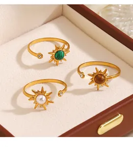 Primer plano de anillos de sol dorados con piedras de colores en un joyero.