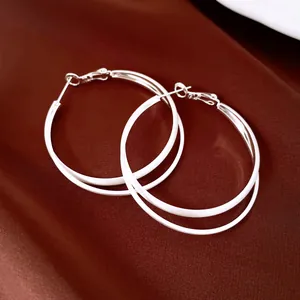 Gros plan détaillé d'élégantes boucles d'oreilles créoles en argent sur du satin luxueux