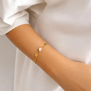 Detailopname van een gouden bedelarmband met hart en zirkoon om een pols