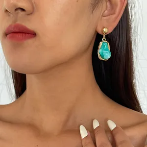 Close-up of vintage geometric earrings with turquoise resin on an elegant model.