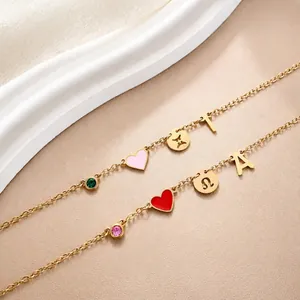 Macro-opname van een gouden armband met kleurrijke hart-, dierenriem- en letterhangers